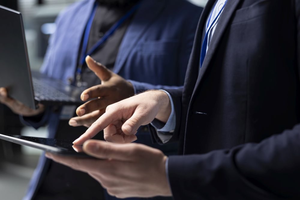 Two people in business attire discuss while one holds a laptop and the other uses a tablet, highlighting the hands-on approach often seen in tech recruitment Singapore professionals use to connect talent with opportunity.